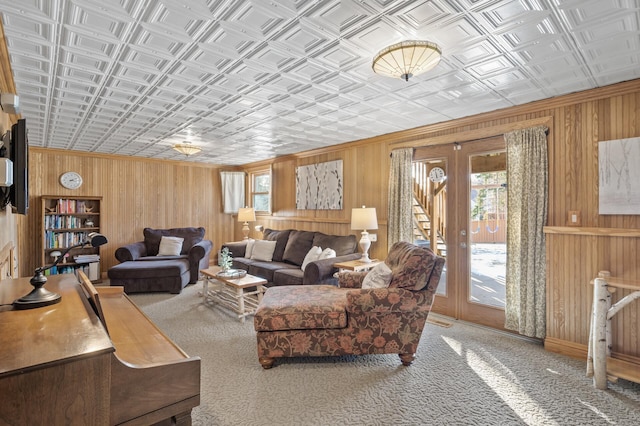 carpeted living room with french doors and wooden walls