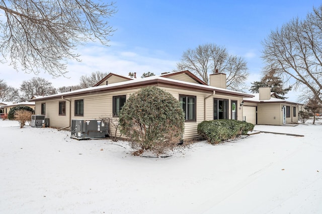 snow covered house featuring central AC unit