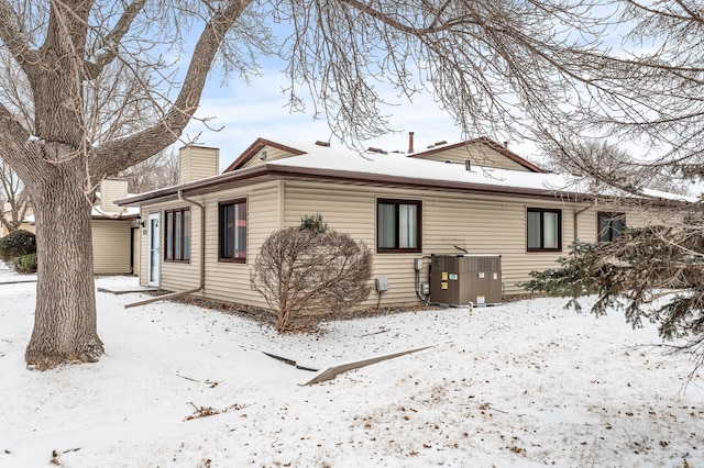 snow covered rear of property with cooling unit