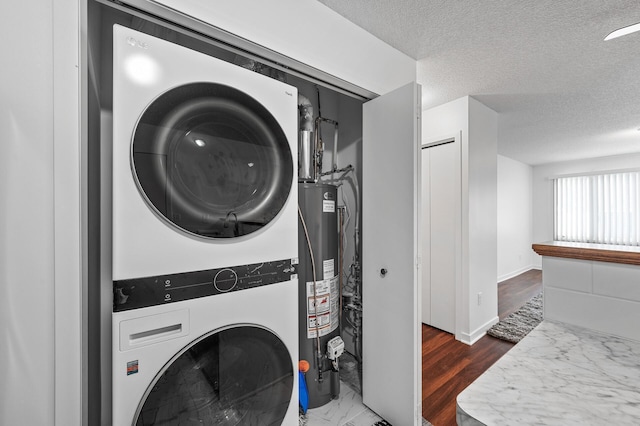 laundry room with dark wood-type flooring, stacked washer and clothes dryer, a textured ceiling, and gas water heater