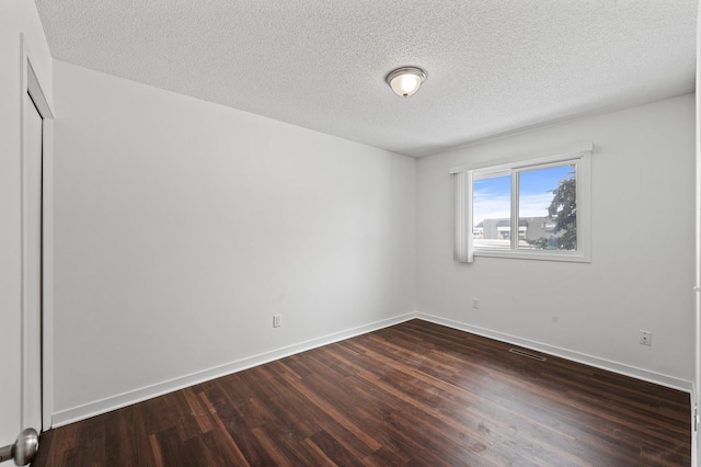 empty room featuring dark hardwood / wood-style flooring and a textured ceiling