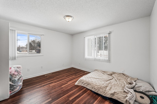 bedroom with dark wood-type flooring and a textured ceiling