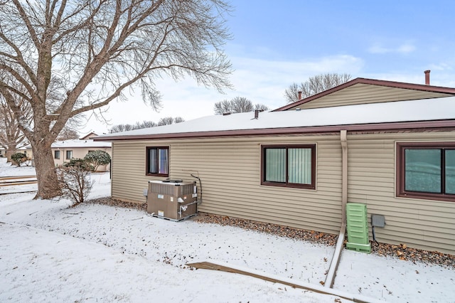 snow covered house featuring central AC unit