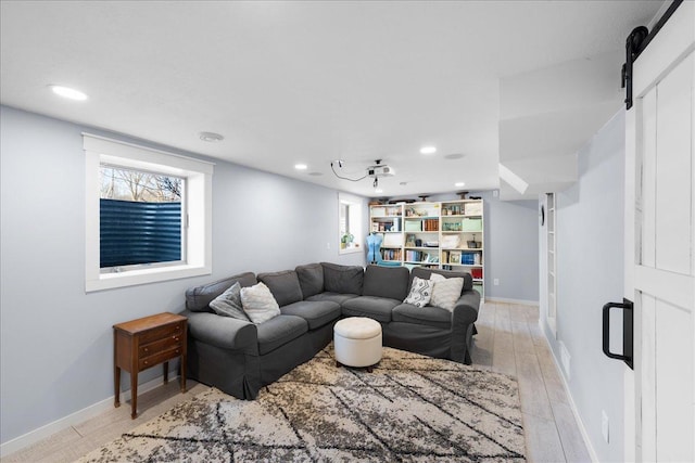 living room with a wealth of natural light, a barn door, and light wood-type flooring