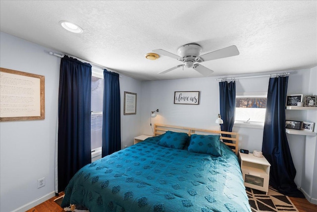 bedroom featuring ceiling fan, wood-type flooring, and a textured ceiling