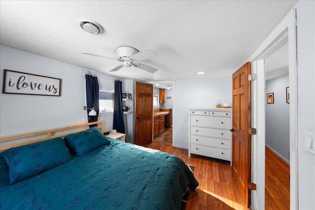 bedroom with hardwood / wood-style flooring, ceiling fan, connected bathroom, and a textured ceiling