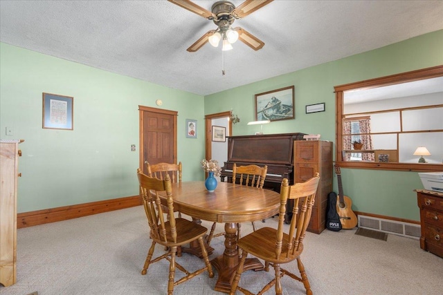 dining area featuring light carpet, a textured ceiling, visible vents, and baseboards