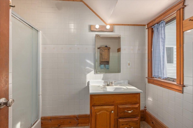 full bath with an enclosed shower, vanity, and tile walls