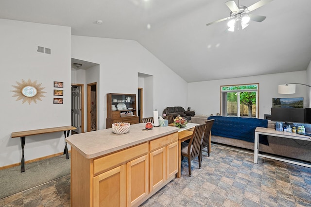 kitchen with vaulted ceiling, a kitchen island, light brown cabinets, and ceiling fan