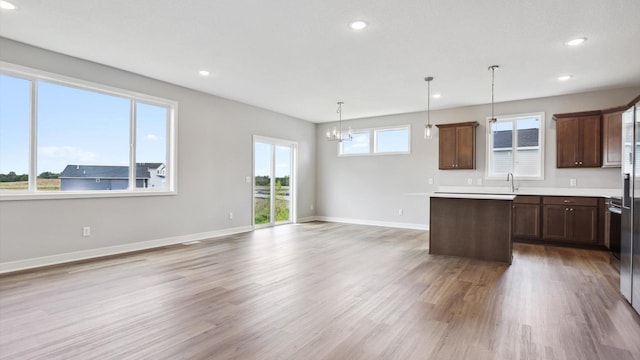 kitchen featuring hanging light fixtures, wood-type flooring, a kitchen island, and sink