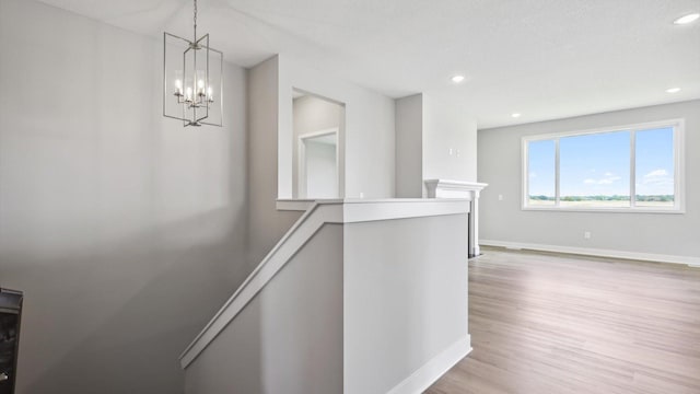 hallway featuring an inviting chandelier and light hardwood / wood-style flooring