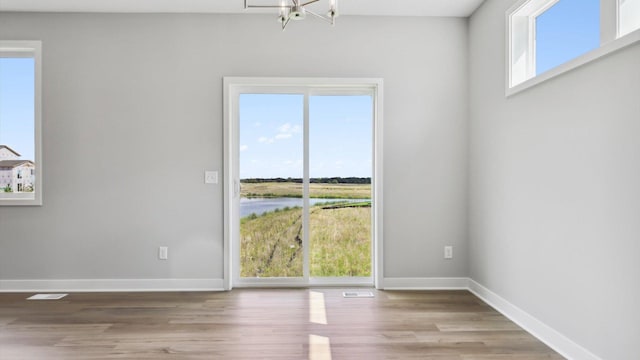 spare room featuring light hardwood / wood-style floors and a chandelier