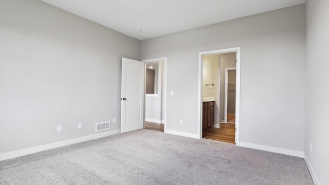 unfurnished bedroom featuring ensuite bathroom and carpet flooring