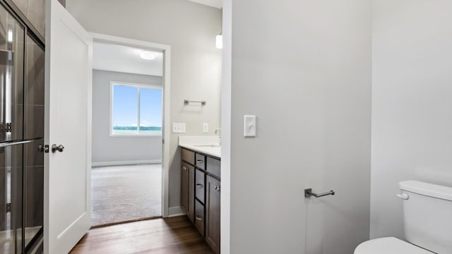 bathroom featuring vanity, toilet, a shower with door, and hardwood / wood-style floors