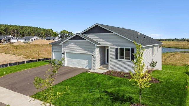 view of front of house with a garage, a water view, and a front lawn