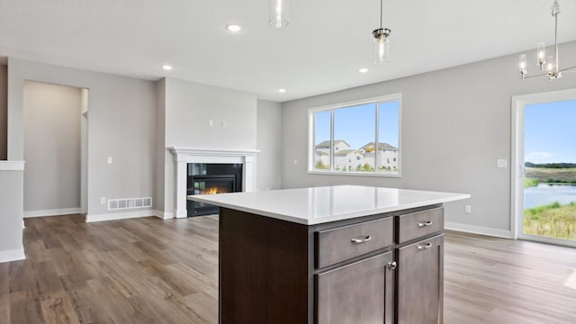 kitchen featuring a center island, dark brown cabinets, pendant lighting, and light hardwood / wood-style floors