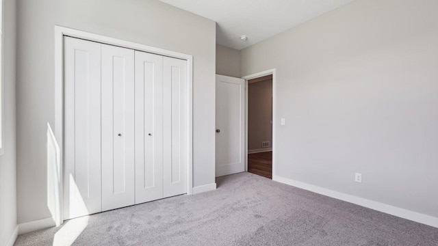 unfurnished bedroom with light colored carpet and a closet