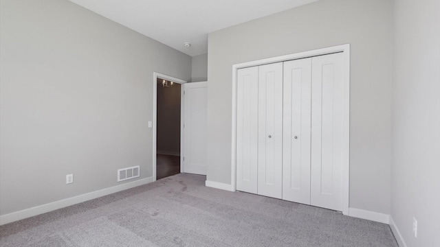 unfurnished bedroom with light carpet and a closet