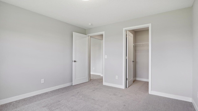 unfurnished bedroom with a walk in closet, light carpet, and a closet