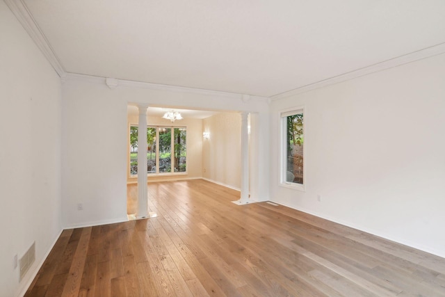 unfurnished room featuring a notable chandelier, crown molding, decorative columns, and light hardwood / wood-style floors