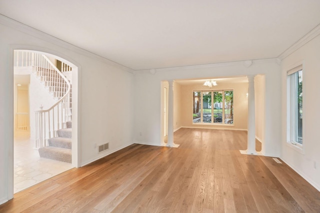 interior space with decorative columns, ornamental molding, an inviting chandelier, and light wood-type flooring