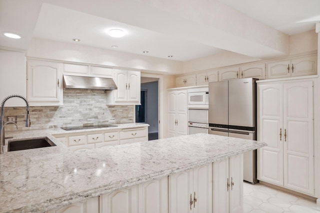 kitchen with sink, stainless steel fridge, backsplash, white microwave, and black electric stovetop