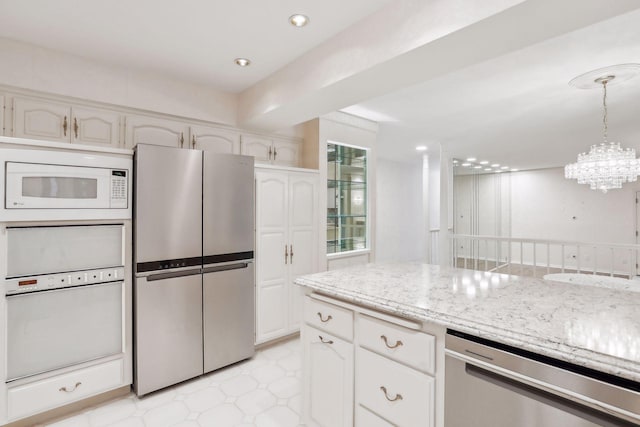 kitchen featuring white cabinetry, hanging light fixtures, appliances with stainless steel finishes, a notable chandelier, and light stone countertops