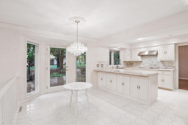 kitchen featuring sink, black electric stovetop, white cabinets, decorative light fixtures, and kitchen peninsula