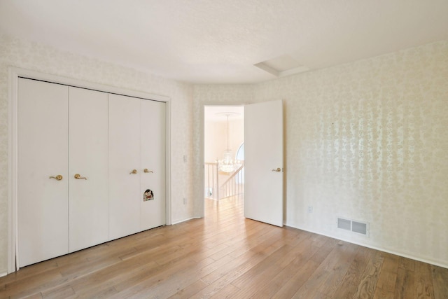 unfurnished bedroom with a closet and light wood-type flooring