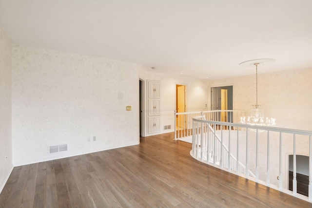 unfurnished room with wood-type flooring and a notable chandelier