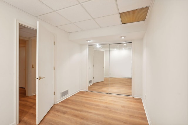 spare room featuring a drop ceiling and light hardwood / wood-style floors