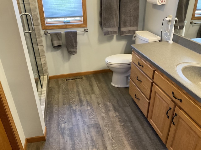 bathroom with vanity, hardwood / wood-style floors, an enclosed shower, and toilet