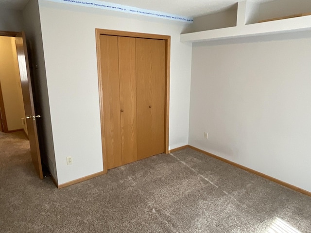 unfurnished bedroom with a closet and dark colored carpet