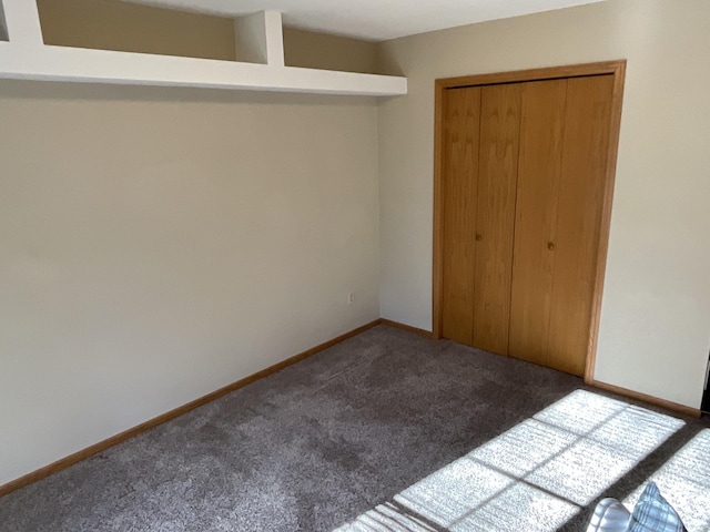 unfurnished bedroom featuring a closet and dark colored carpet