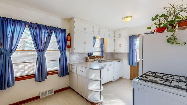 kitchen with a healthy amount of sunlight, sink, white cabinets, and white appliances