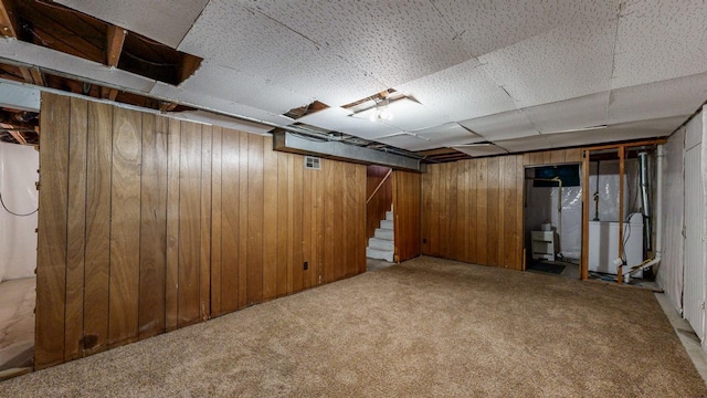 basement with heating unit, wooden walls, and light colored carpet