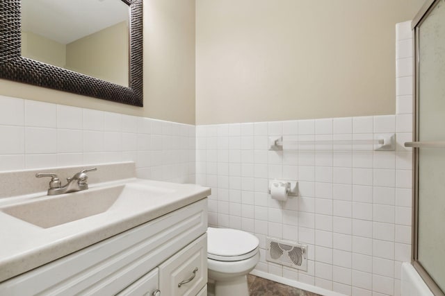 full bathroom featuring bath / shower combo with glass door, vanity, toilet, and tile walls