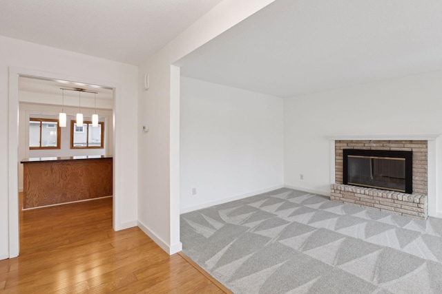 unfurnished living room featuring a brick fireplace and light wood-type flooring