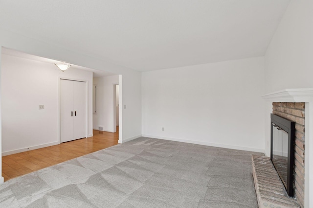 unfurnished living room with light carpet and a brick fireplace