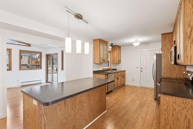 kitchen with appliances with stainless steel finishes, pendant lighting, baseboard heating, kitchen peninsula, and light hardwood / wood-style flooring