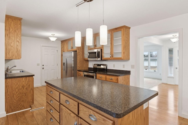 kitchen with appliances with stainless steel finishes, a center island, sink, and light wood-type flooring