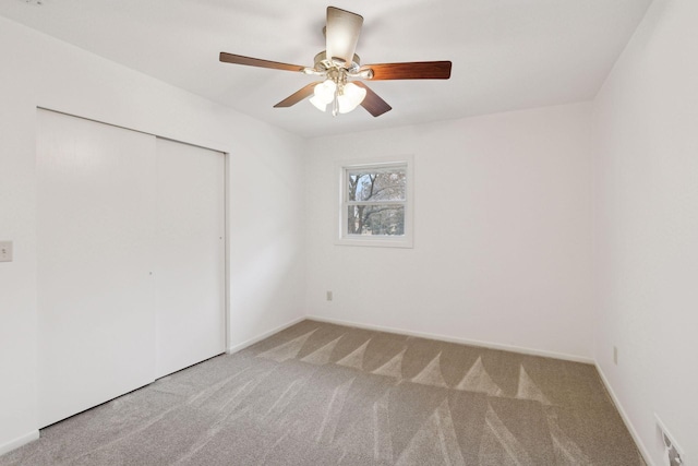 unfurnished bedroom featuring light colored carpet, ceiling fan, and a closet