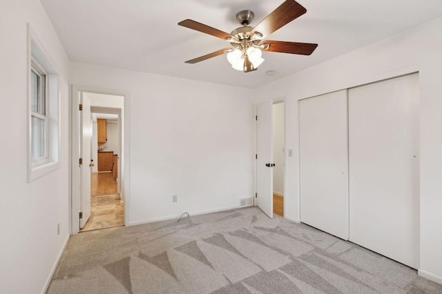 unfurnished bedroom featuring light colored carpet, a closet, and ceiling fan