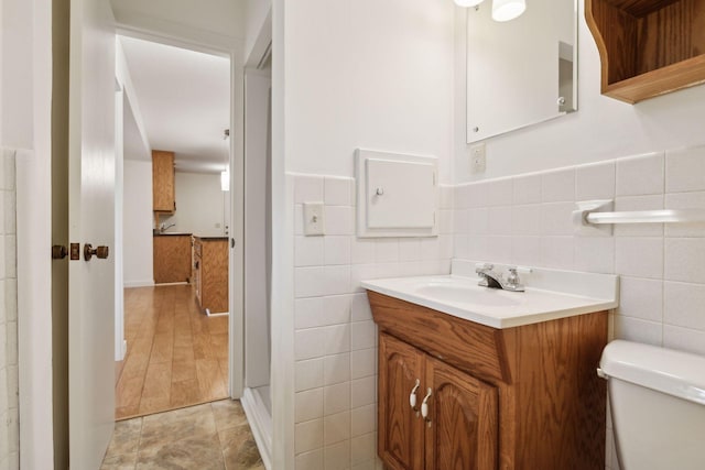 bathroom with vanity, toilet, and tile walls