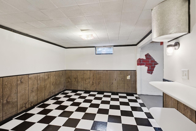 basement featuring crown molding and wooden walls