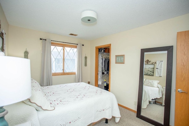 carpeted bedroom with a walk in closet, a textured ceiling, and a closet