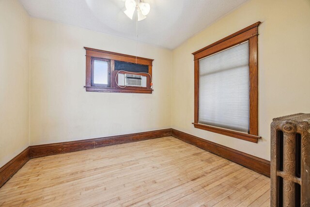 unfurnished room with radiator, ceiling fan, baseboards, and hardwood / wood-style flooring