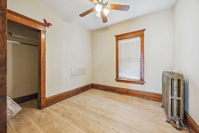 unfurnished bedroom featuring radiator, light wood-style flooring, and baseboards