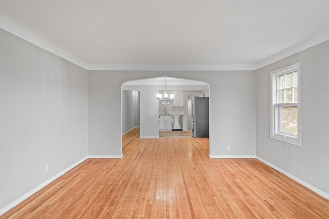 unfurnished living room featuring sink, light hardwood / wood-style flooring, and a notable chandelier