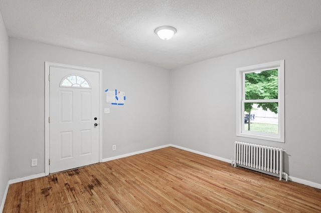 foyer entrance with radiator, light hardwood / wood-style flooring, and a textured ceiling